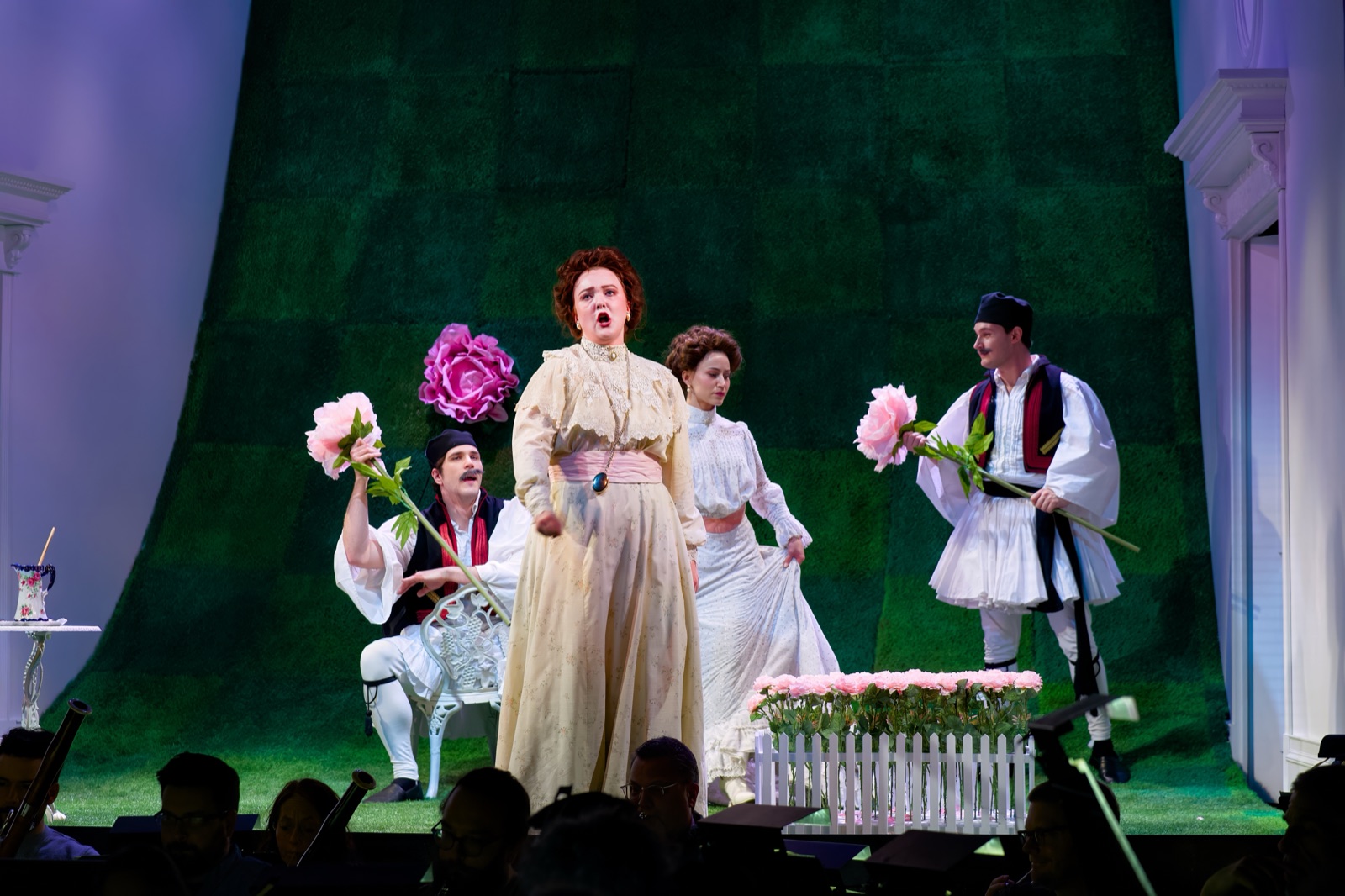 Veronica Richer in a cream dress on stage with pink flowers