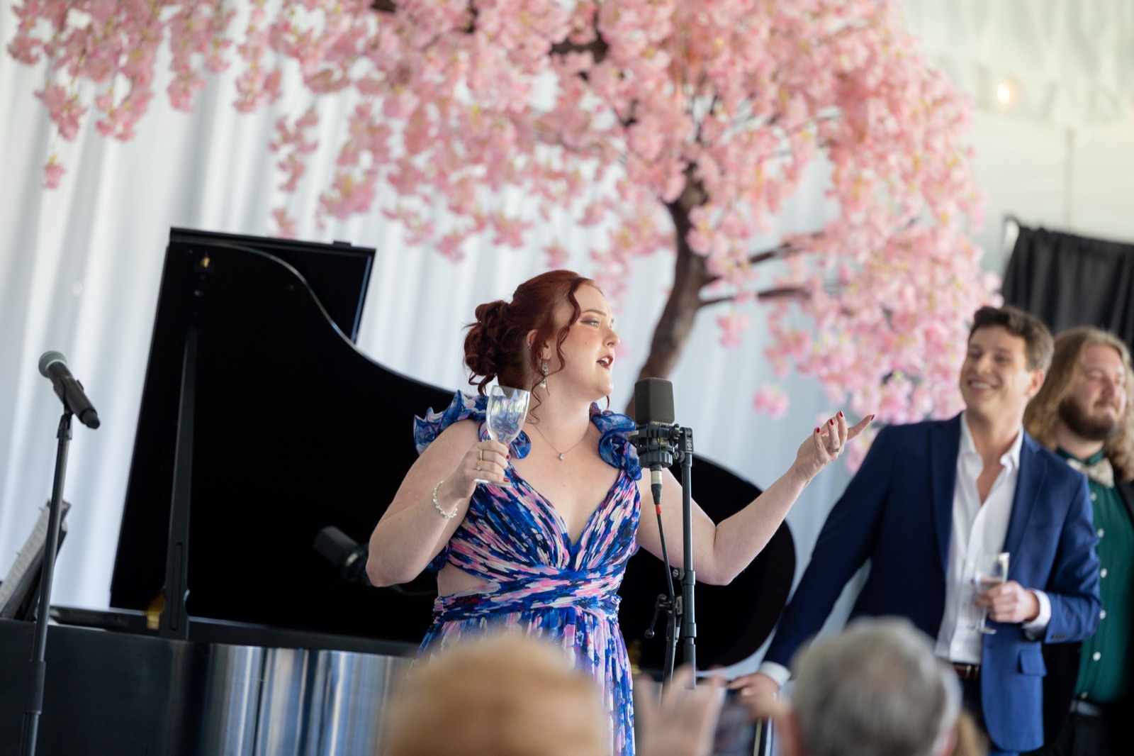 Veronica Richer singing under a cherry blossom tree with piano