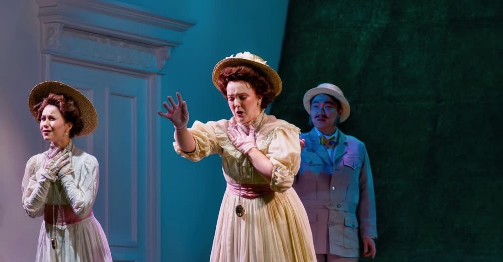 Veronica Richer in a straw hat and cream period dress on stage
